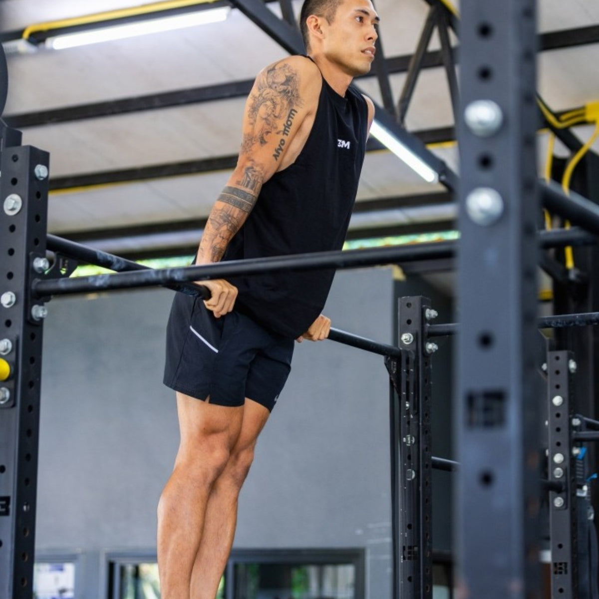 Man in the E3M Training Vest doing dips on parallel bars in a gym