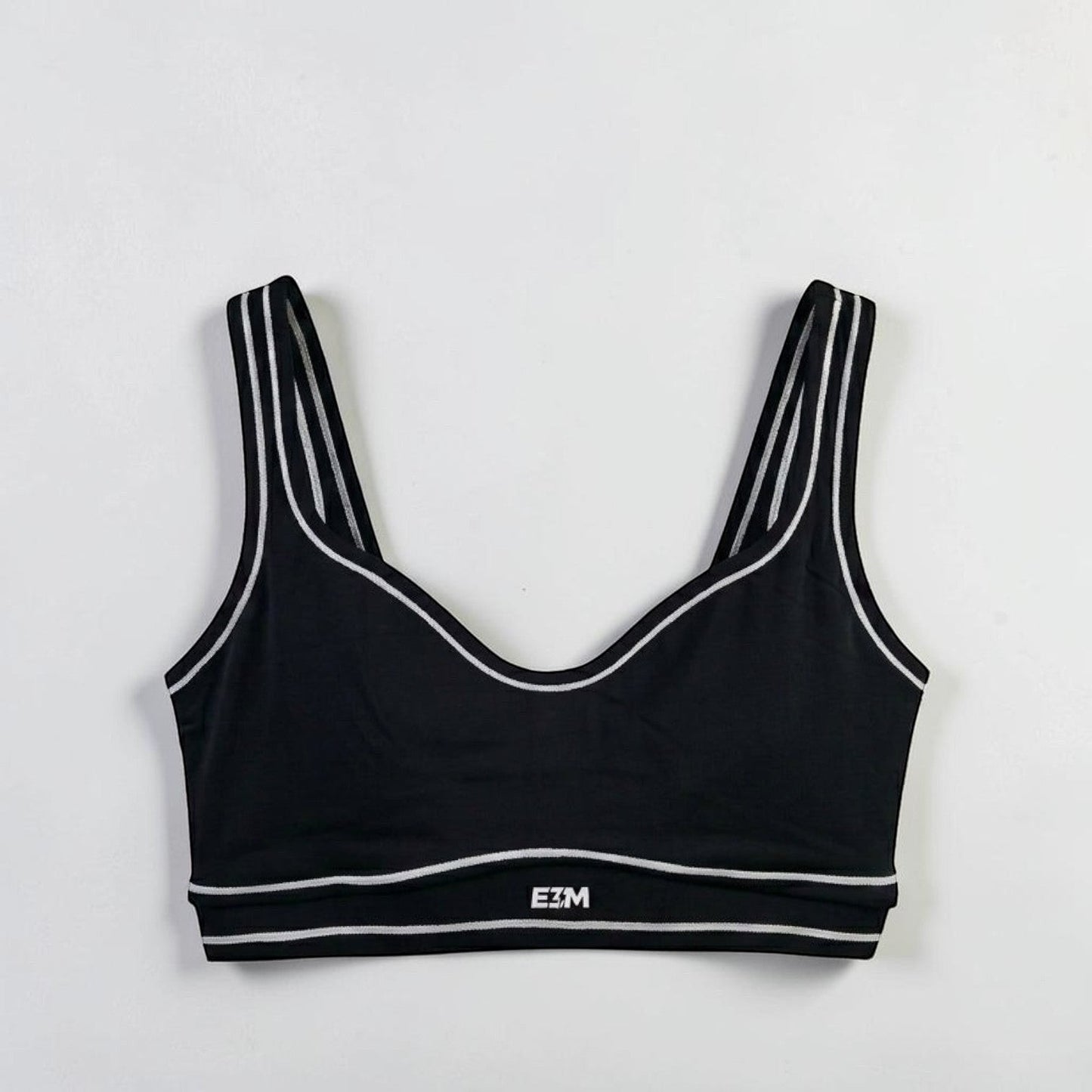E3M Pre-workout black performance sports bra with white striped trim and logo detail, made from moisture-wicking fabric.